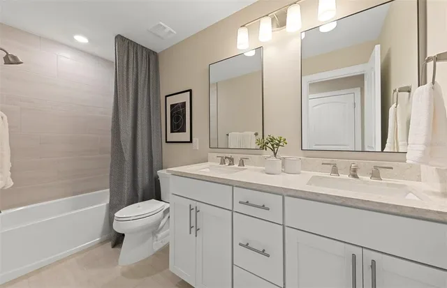 a bathroom with a double vanity sink toilet mirror and bathtub