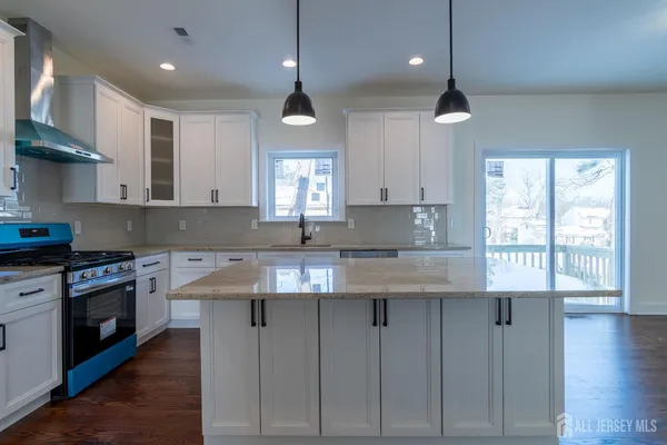 a kitchen with stainless steel appliances granite countertop a sink a stove and a wooden floors