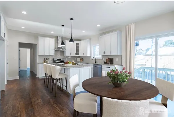 a kitchen with stainless steel appliances granite countertop a refrigerator a sink dishwasher a stove and white cabinets with wooden floor