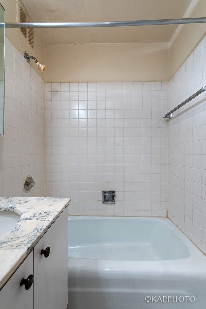 655 West Irving Park Road, Unit 1505 Chicago, IL 60613 - Photo 17 of 26 a bathroom with a granite countertop sink and a bathtub