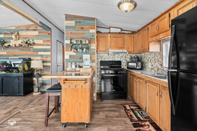 a kitchen with stainless steel appliances a refrigerator a stove a sink and dishwasher with wooden floor