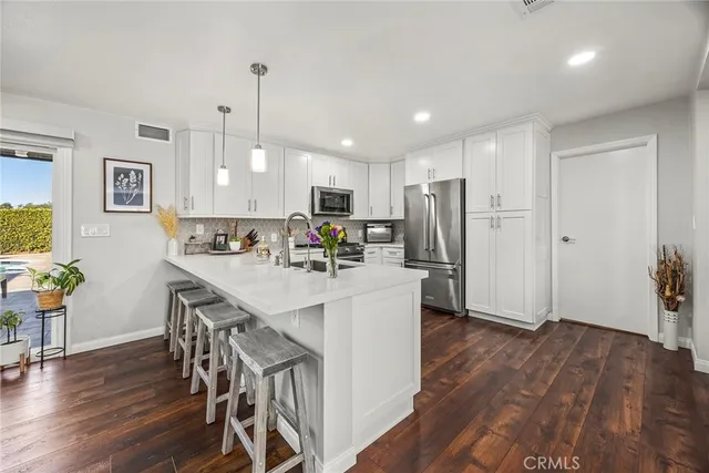a kitchen with stainless steel appliances a dining table chairs refrigerator and sink