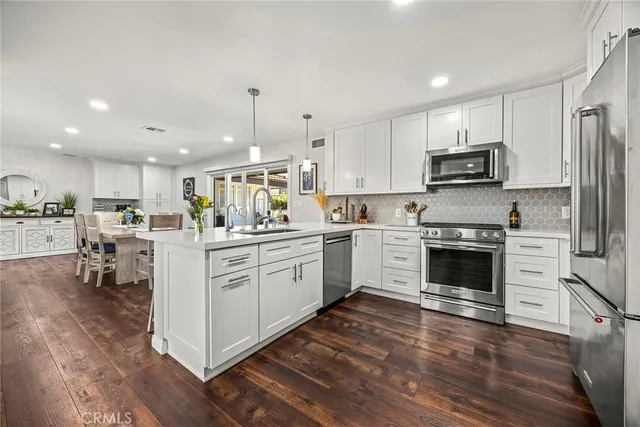 a kitchen with kitchen island granite countertop a sink cabinets and stainless steel appliances