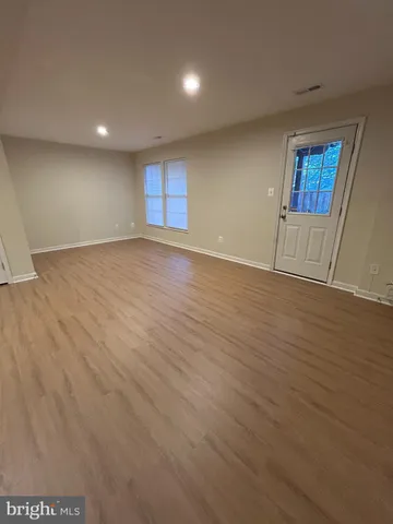 a view of an empty room with wooden floor and windows