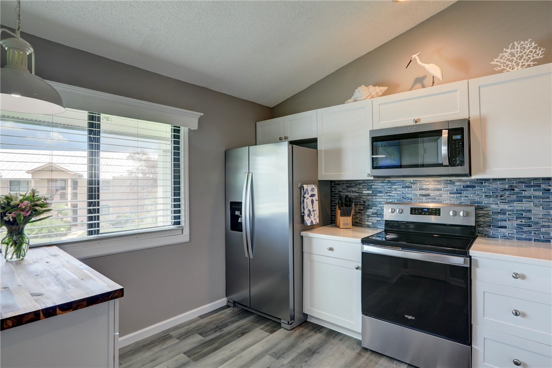 5725 Pelican Pointe Drive, Unit 4 Sebastian, FL 32958 - Photo 16 of 36 a kitchen with stainless steel appliances granite countertop a stove a refrigerator and a microwave