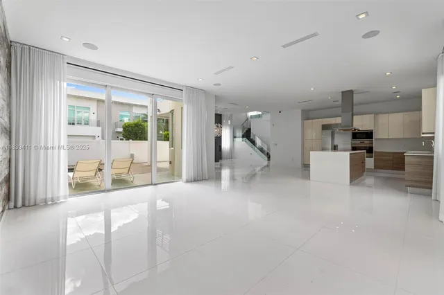 a view of an empty room with wooden floor and windows