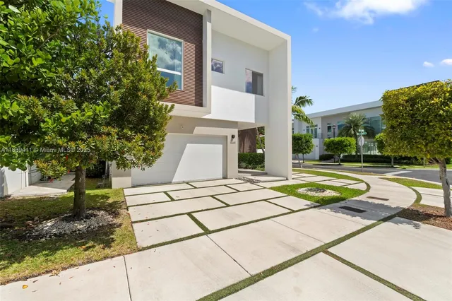 a view of a white building with a yard and plants
