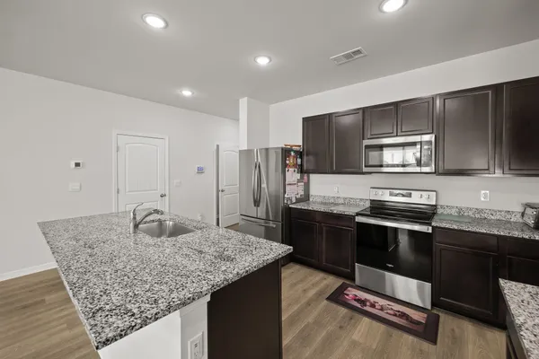 a kitchen with stainless steel appliances granite countertop a sink stove and refrigerator