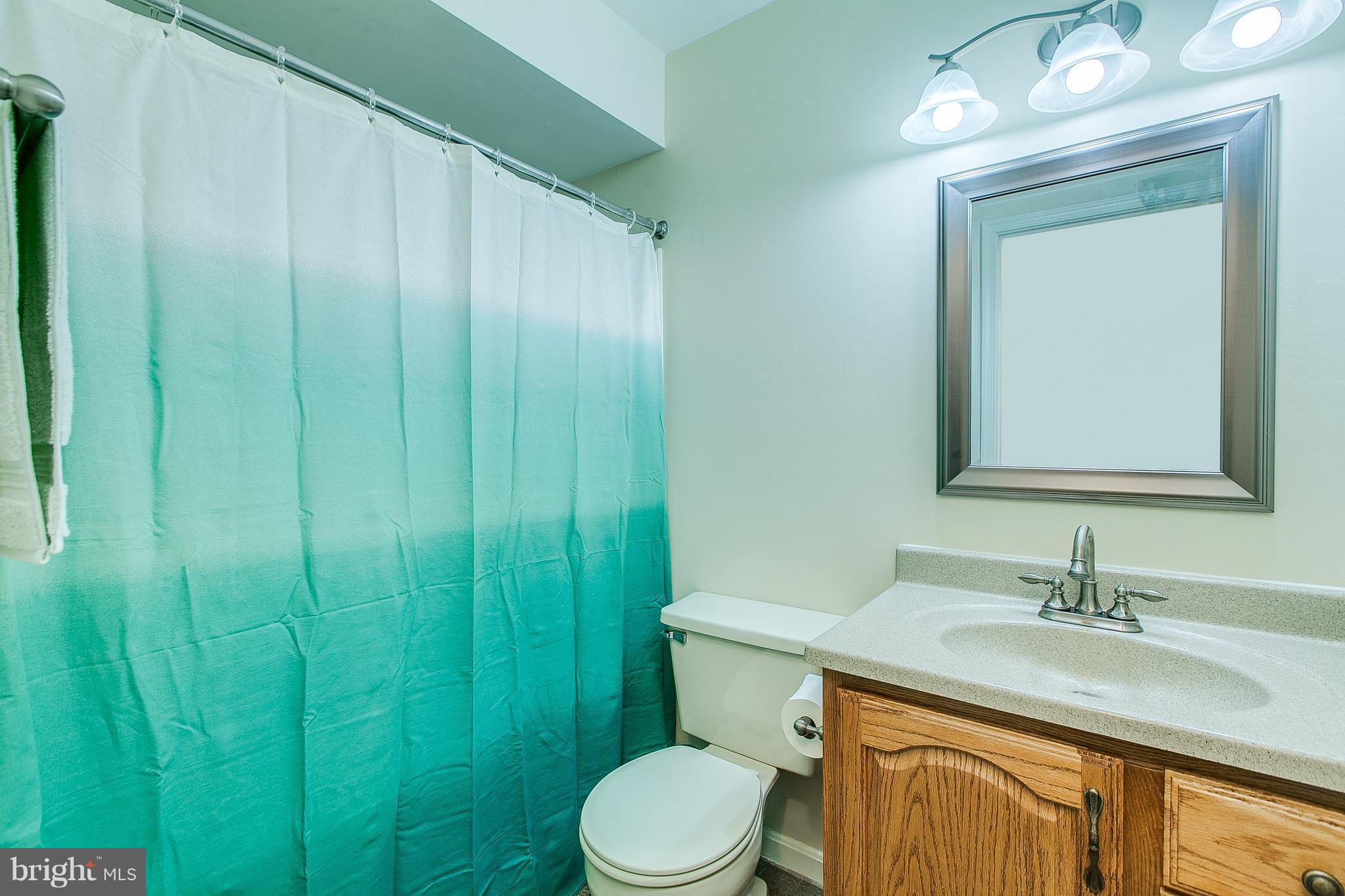 8601 Falls Run Road, Unit F Ellicott City, MD 21043 - Photo 11 of 17 a bathroom with a granite countertop sink a toilet and mirror