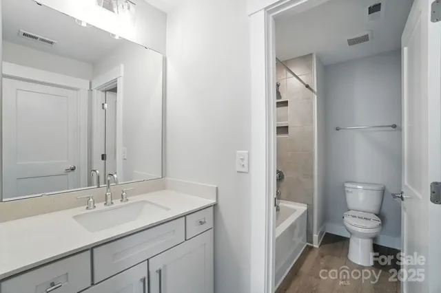 a bathroom with a granite countertop bathtub shower sink vanity mirror and toilet