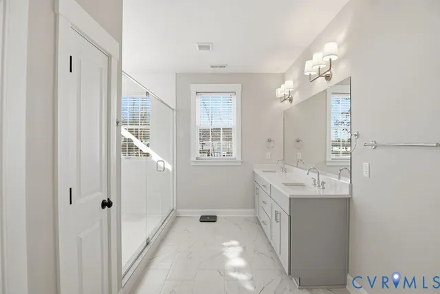a spacious bathroom with a double vanity sink a mirror and a shower