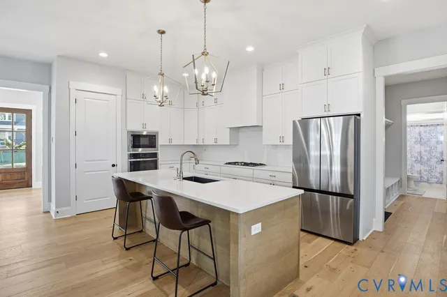 a kitchen with stainless steel appliances granite countertop a refrigerator a sink dishwasher a stove and a refrigerator with wooden floor