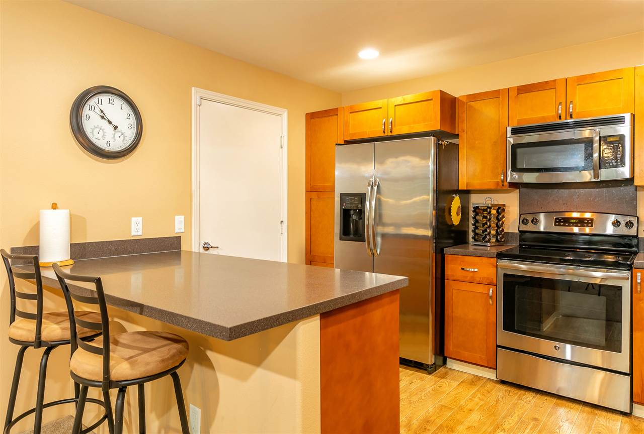 209 Alake Street Kahului, HI 96732 - Photo 3 of 30 a kitchen with stainless steel appliances granite countertop a refrigerator a stove and a microwave with wooden floor