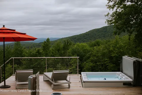 a view of a patio with a dining table and chairs under an umbrella with large trees