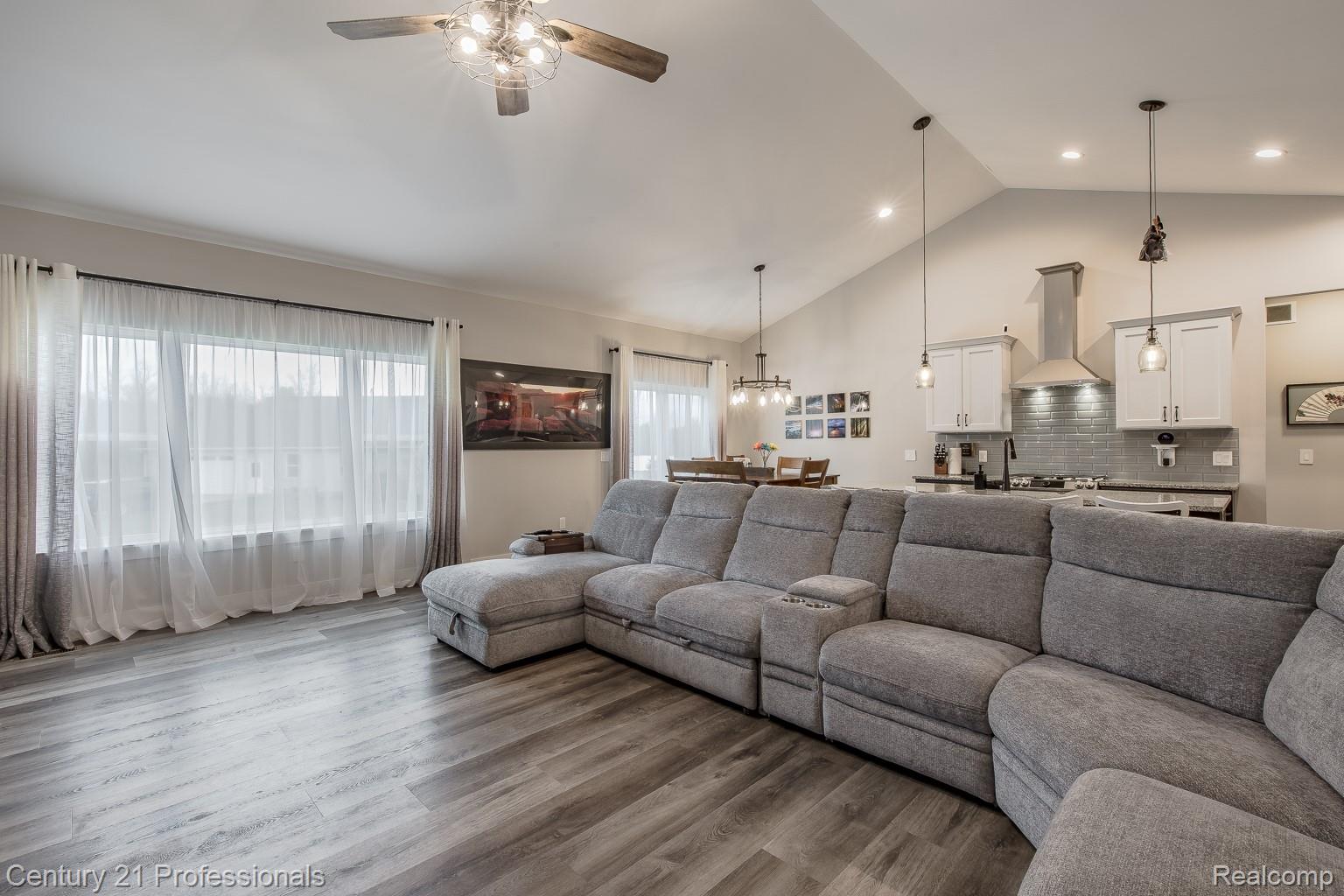 4914 TORATOLA Lane Howell, MI 48843 - Photo 10 of 39 Living room featuring a high ceiling, a ceiling fan, and wood finished floors