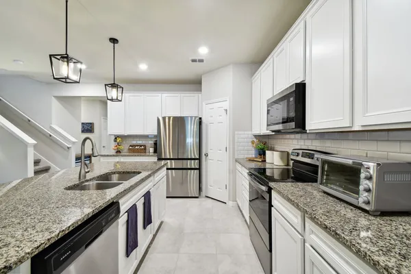 a kitchen with stainless steel appliances granite countertop stove a sink a microwave oven a dining table and chairs with wooden floor