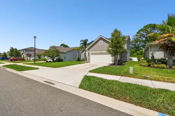 a view of a house with a yard and potted plants
