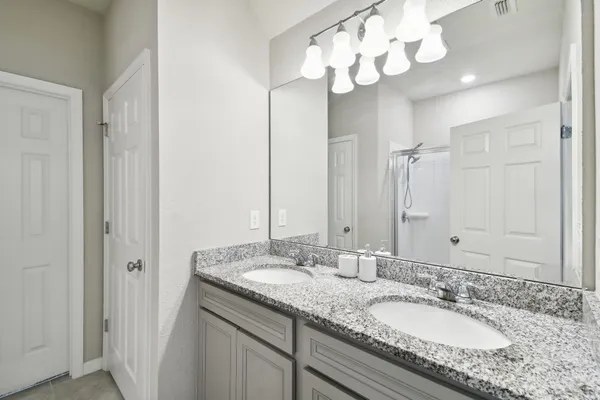 a bathroom with a granite countertop double vanity and a mirror