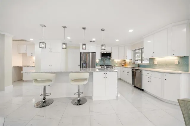 a large kitchen with stainless steel appliances kitchen island granite countertop a sink a stove and a refrigerator