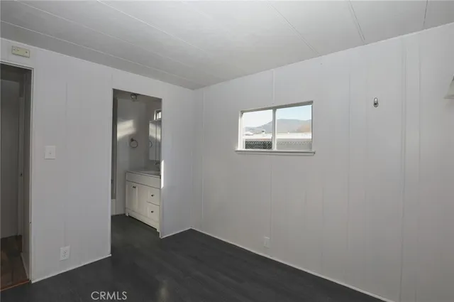 an empty room with wooden floor closet and windows