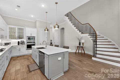 a large kitchen with stainless steel appliances kitchen island granite countertop a sink and dishwasher a oven with white cabinets