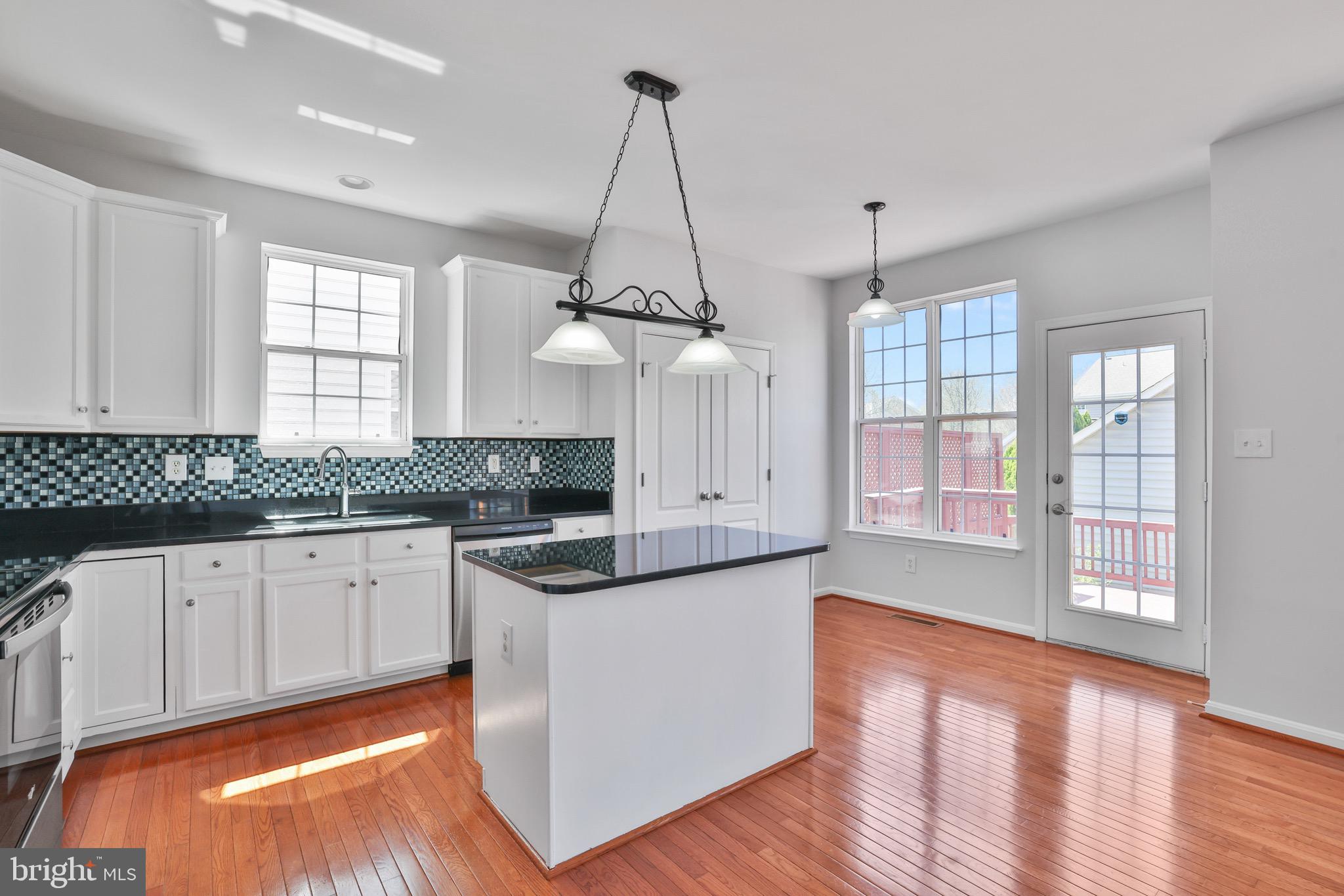 26215 Ocala Circle Chantilly, VA 20152 - Photo 23 of 50 a kitchen with granite countertop a stove a sink and white cabinets with wooden floor