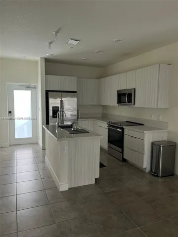 a kitchen with kitchen island granite countertop a stove top oven a sink dishwasher and a refrigerator