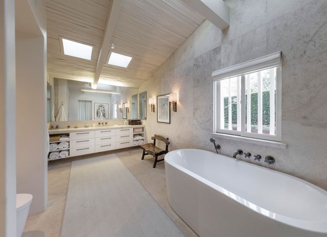 a spacious bathroom with a tub double vanity and windows