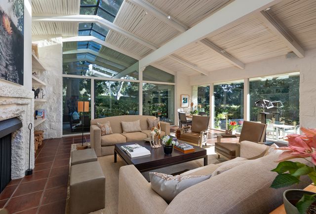 a living room with furniture large windows and fireplace