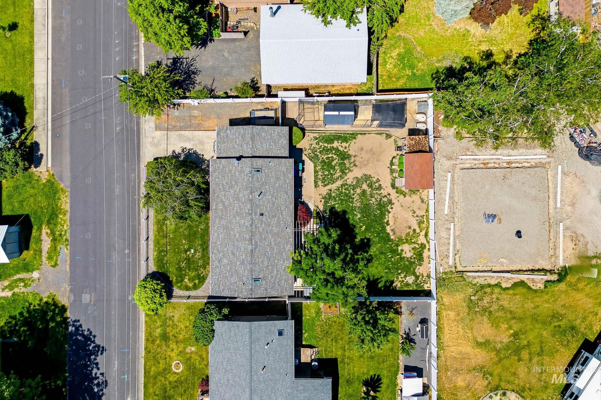 3715 18th Street Lewiston, ID 83501 - Photo 28 of 30 Aerial view of the property showcasing the main residence with a gray shingle roof, a paved driveway, and a fenced backyard