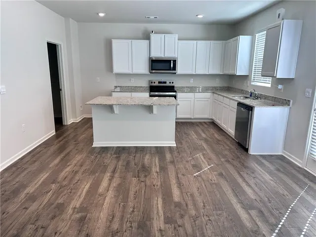 a large kitchen with cabinets wooden floor and stainless steel appliances