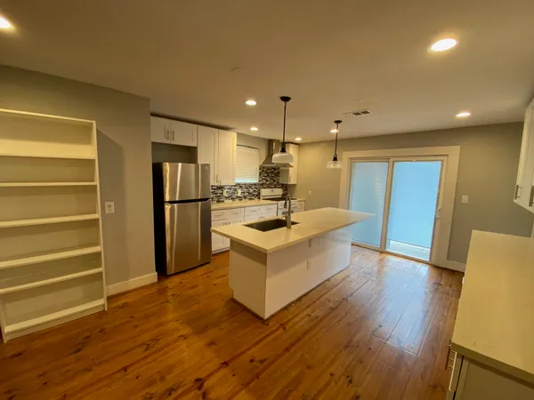 a large white kitchen with wooden floors and stainless steel appliances
