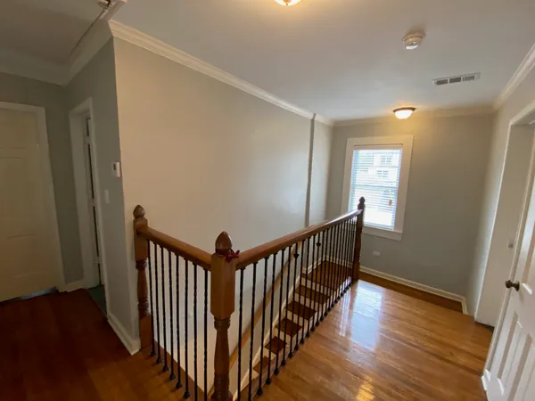 a view of a hallway with wooden floor and stairs
