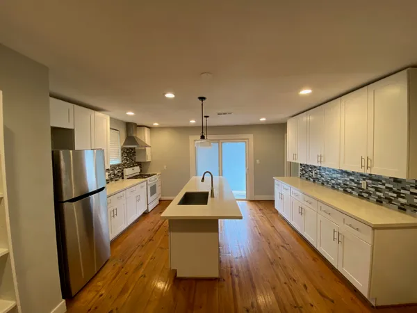 a kitchen with stainless steel appliances granite countertop a refrigerator a stove and a wooden floors