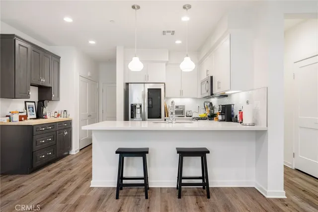 a kitchen with stainless steel appliances a table chairs refrigerator and sink