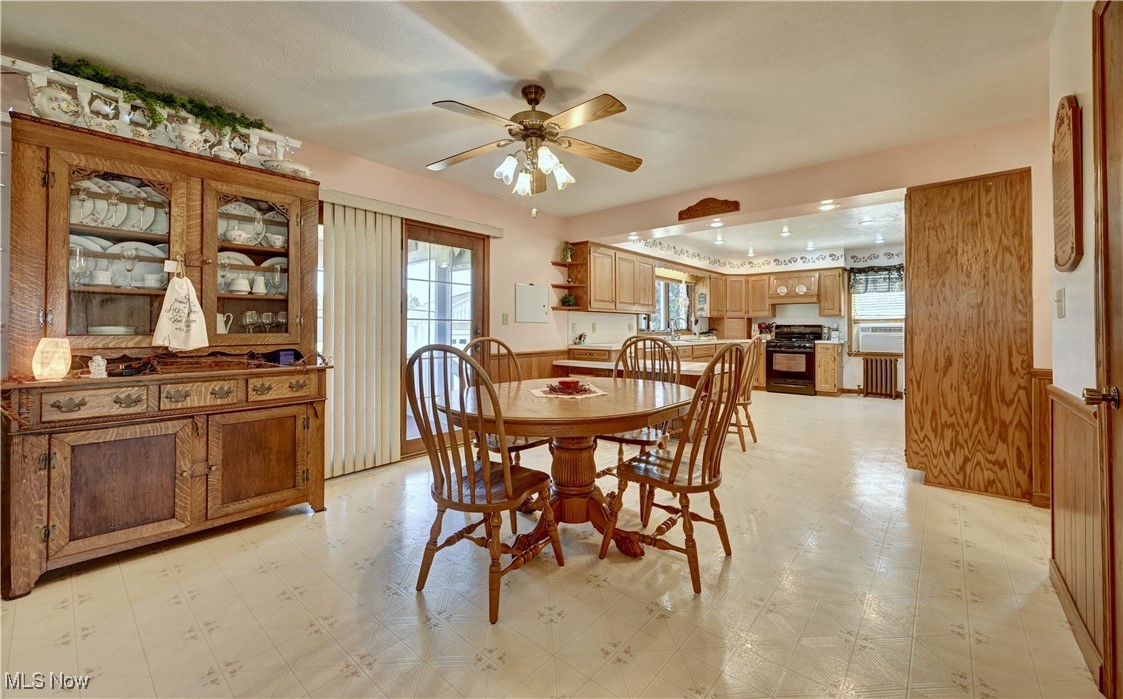 17198 Harrison Road Navarre, OH 44662 - Photo 20 of 45 Dining area featuring light flooring, a wainscoted wall, radiator, a ceiling fan, and wooden walls