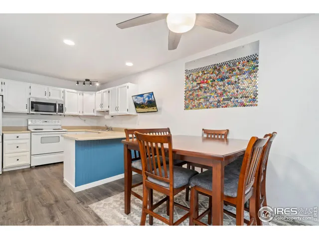 a kitchen with stainless steel appliances kitchen island granite countertop a dining table chairs and white cabinets