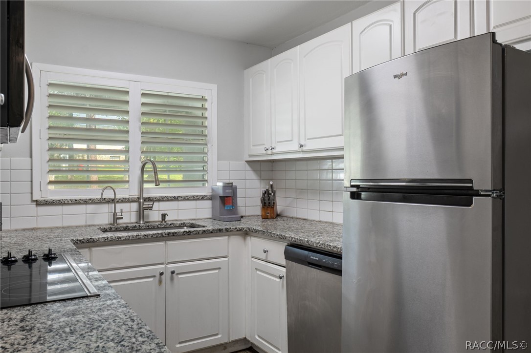 1140 South Highlands Avenue Inverness, FL 34452 - Photo 15 of 54 a kitchen with granite countertop a refrigerator sink and white cabinets