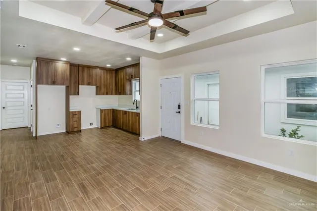 a view of empty room with kitchen and window