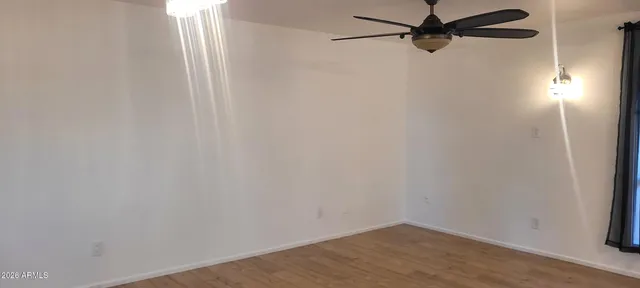 an empty room with wooden floor fan and windows