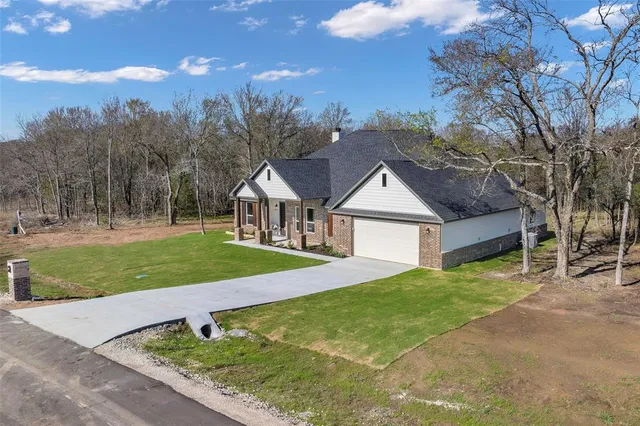 a view of a house with a yard and large tree