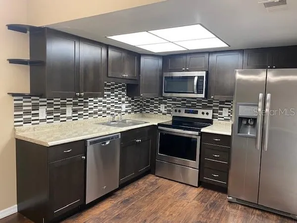 a kitchen with stainless steel appliances kitchen island granite countertop a stove a sink and a refrigerator