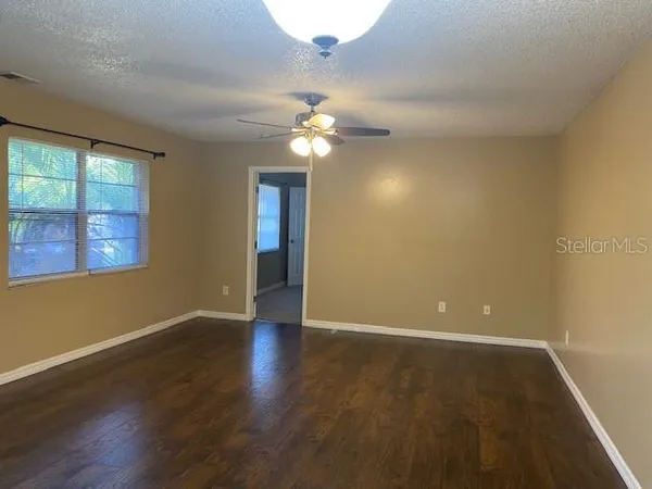 a view of a livingroom with a ceiling fan window and wooden floor