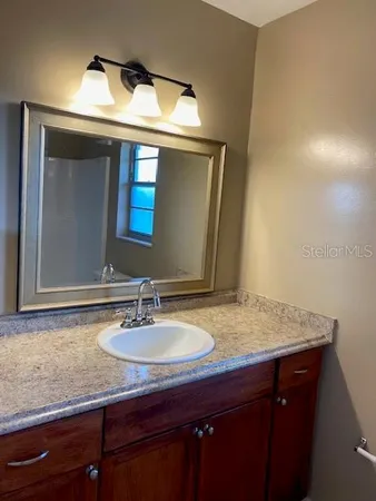 a bathroom with a granite countertop sink and a mirror