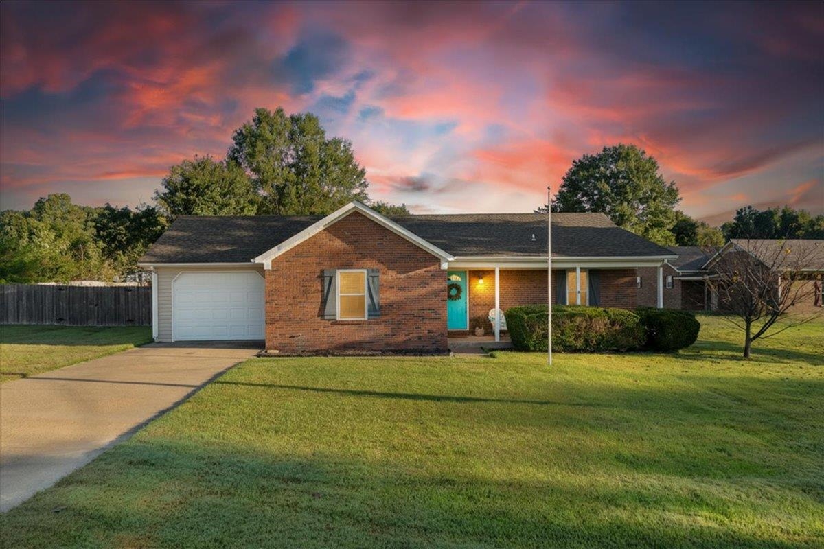 Ranch-style home featuring driveway, brick siding, a porch, and an attached garage