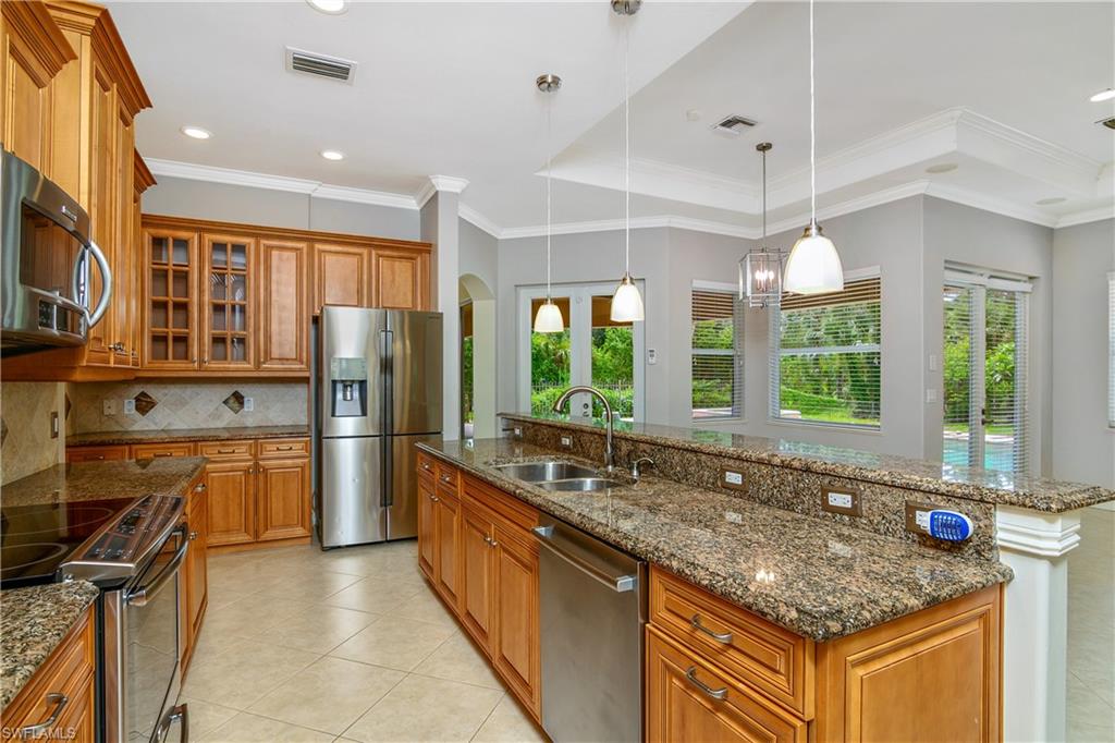 4430 Pine Ridge Road Naples, FL 34119 - Photo 12 of 35 a kitchen with stainless steel appliances granite countertop a stove and refrigerator