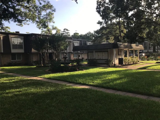 a view of a house with a big yard and large trees