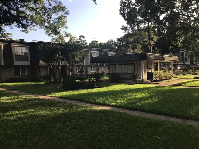a view of a house with a big yard and large trees
