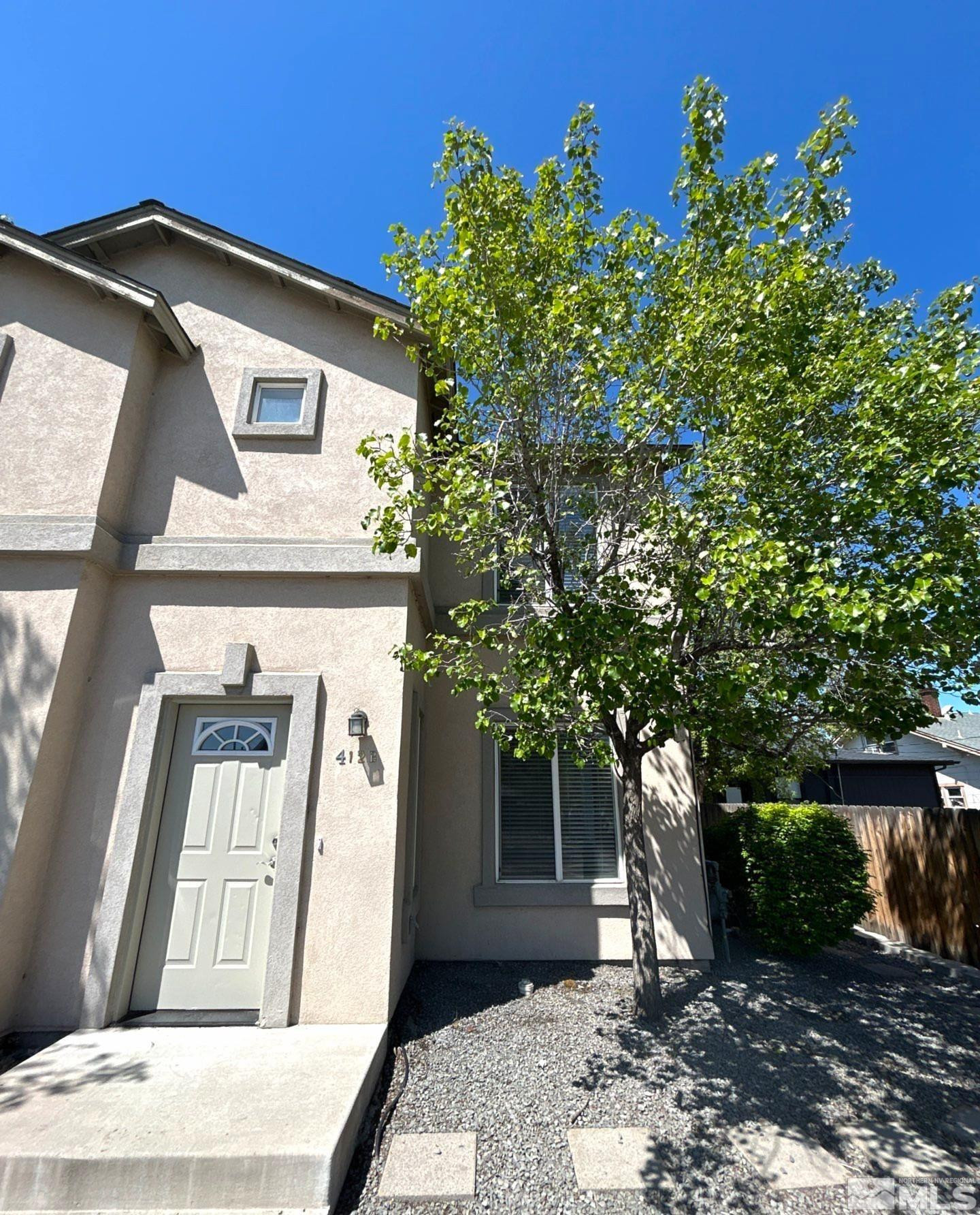 a front view of a house with a tree