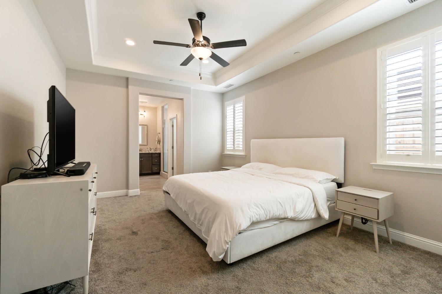 639 Mesa Drive Madera, CA 93636 - Photo 21 of 33 a bedroom with a large bed a flat tv screen and a ceiling fan